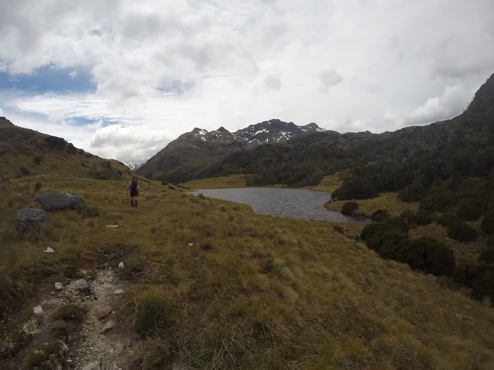 The Hardest Hike in New Zealand // Dusky Track, Tim Ashelford, Photo by Mitch Stewart, hiker, lake, cloudy, heath, grassland, track, snow, mountains
