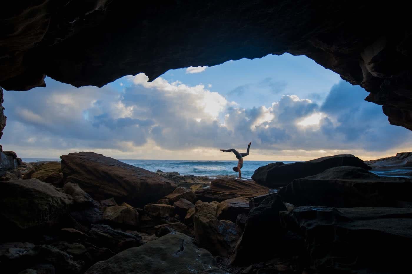 Jacquie Tapsall // Explorer Of The Month - February '18, Yuraygir NP, girl, yoga, handstand, cave, ocean, clouds, sky
