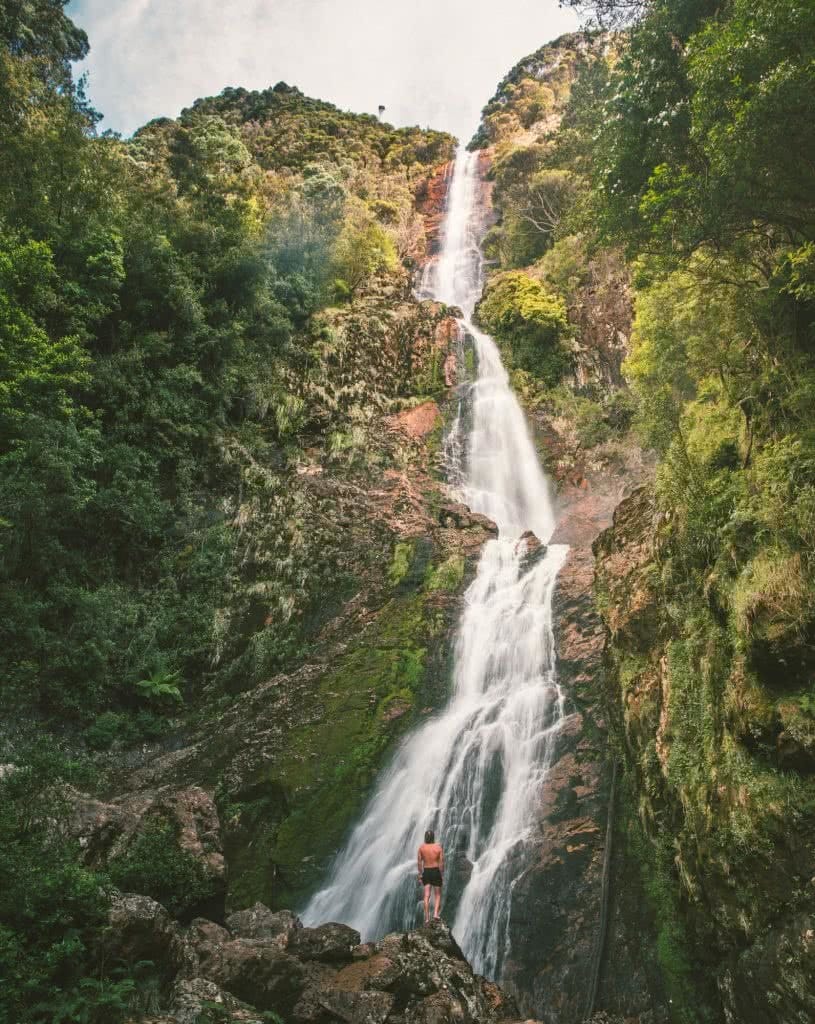 12 Things To Do On Tassie’s West Coast, photo by Mitch Cox, Montezuma Falls, waterfall, man, cliff, mountain, forest