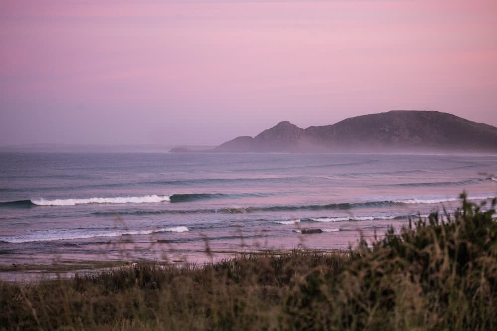 12 Things To Do On Tassie’s West Coast, Green Point Beach, ocean, waves, sunset, pink sky, grass, beach