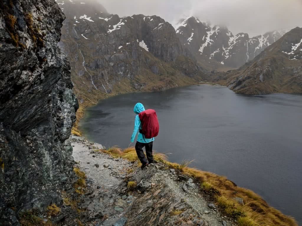 Soggy, Snowbound And Stoked // Routeburn Track (NZ), Rachel Dimond, Day 2 - The Saddle and Harris Lake 2, rain gear, backpack, rain cover, lake, snowcapped mountains