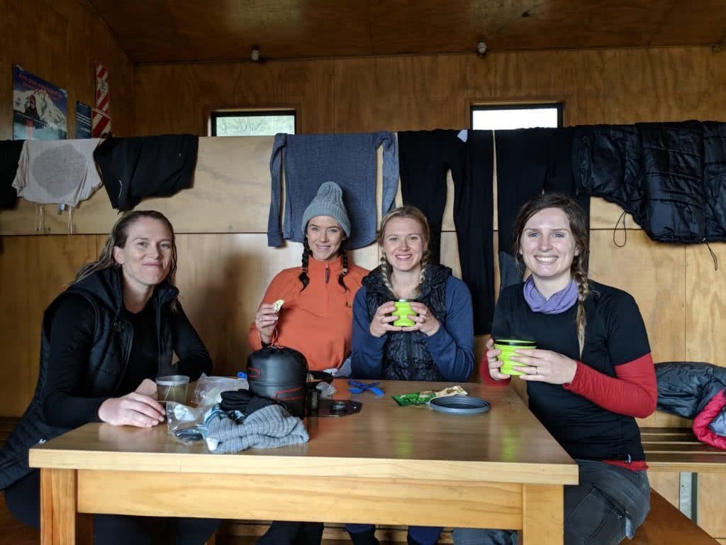 Soggy, Snowbound And Stoked // Routeburn Track (NZ), Rachel Dimond, Day 1 - Routeburn Falls Hut, girls, hikers, crew, friends, tea, rest stop, smiles, table