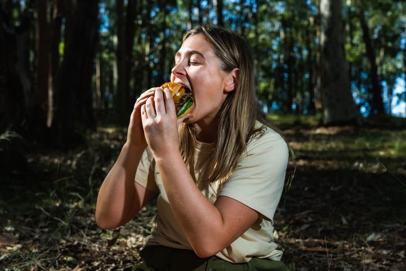 Get Your Mouth Around This Egg-In-A-Hole Burger, photo by Jonathan Tan, woman, burger, bush, bite
