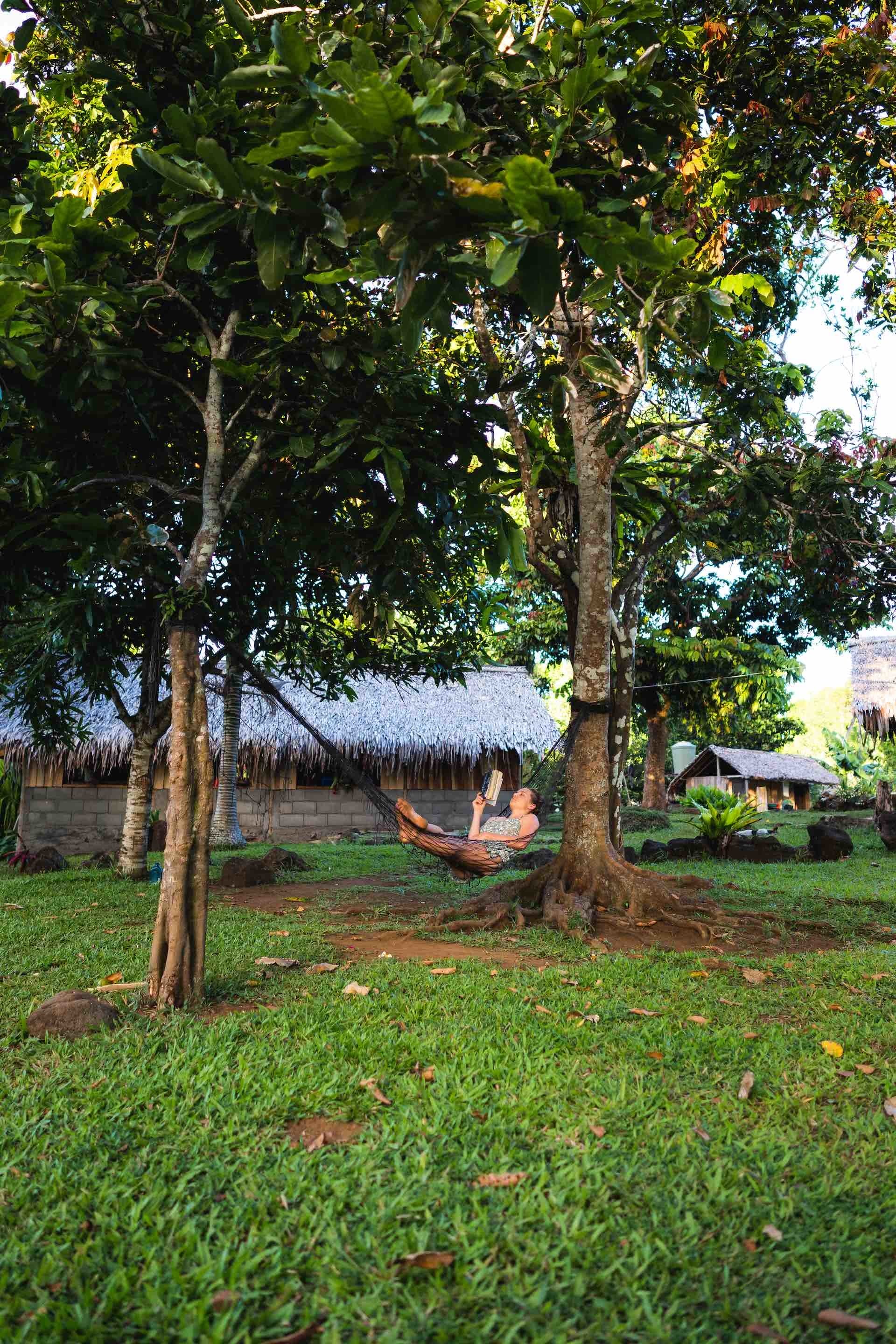 The Best Places to Stay in the Outer Islands of Vanuatu, photos by Ben Savage and Ain Raadik, Ruby Claire, Gaua, Weul Bungalow, hammock, reading, book, woman, palm trees, garden