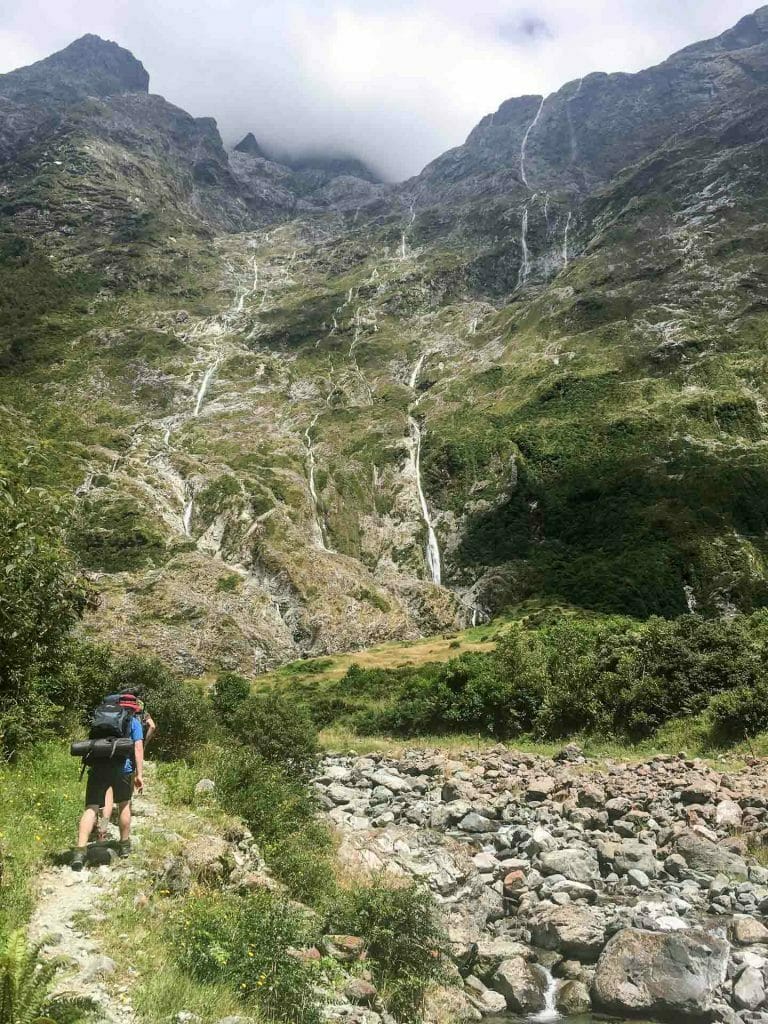 How To Squeeze Three of New Zealand’s ‘Great Walks’ Into Under Two Weeks, Bree Townsend, Milford Track, waterfalls, cliff, person, mountain