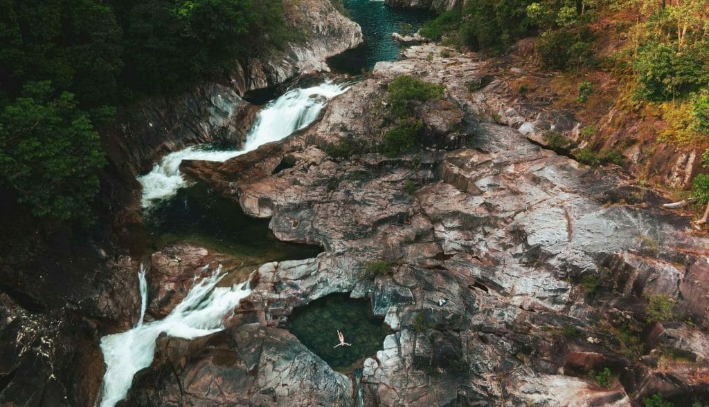 Wild Swimming at Behana Gorge and Clamshell Falls, photo by Mitch Cox, drone shot, waterfall, floating, woman, swim, TTNQ