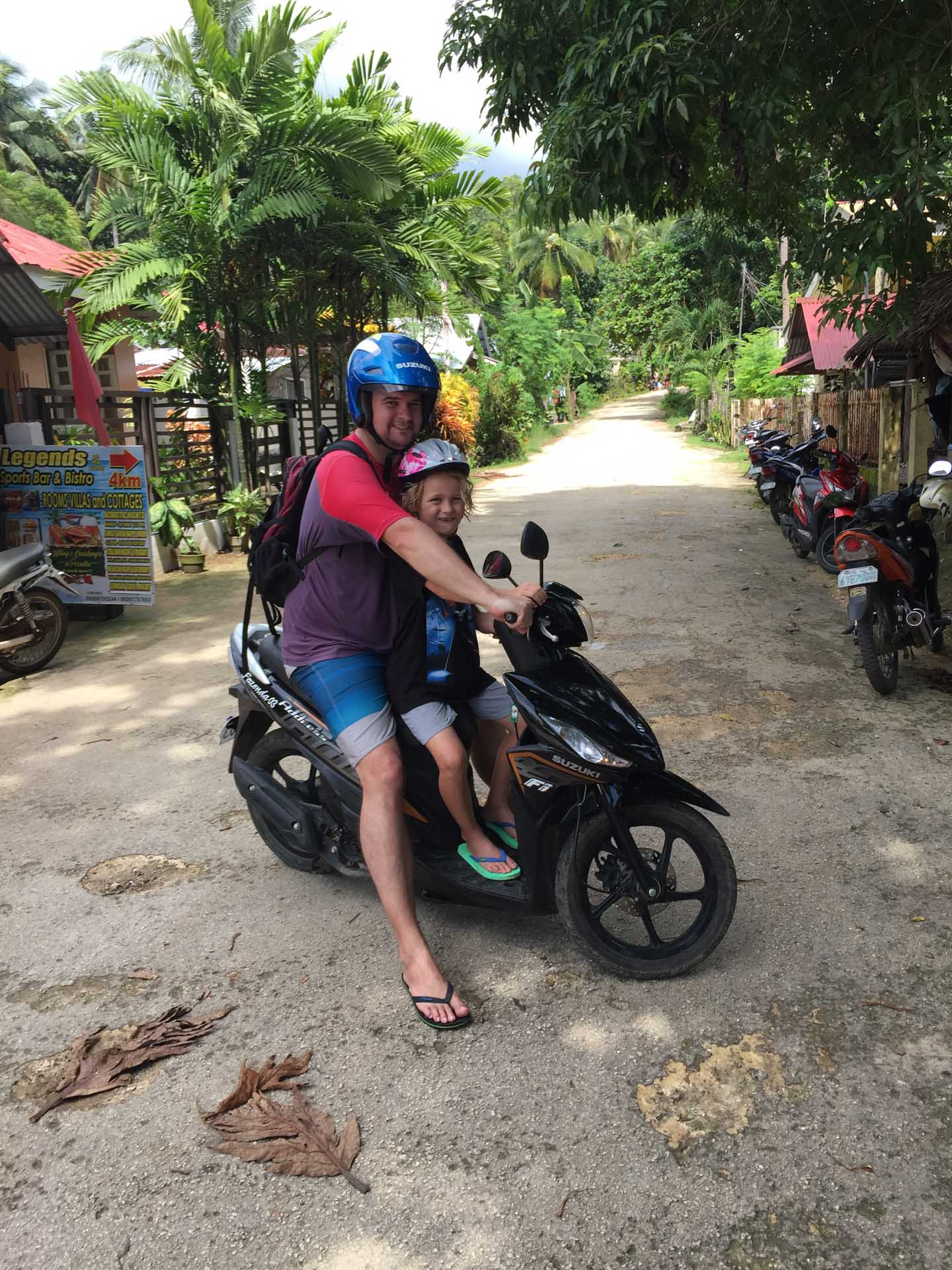 How Being an Expat Changed my Perspective on Adventure, Sarah Schmitt, father and child on a motorbike, the philippines, street, palmtrees