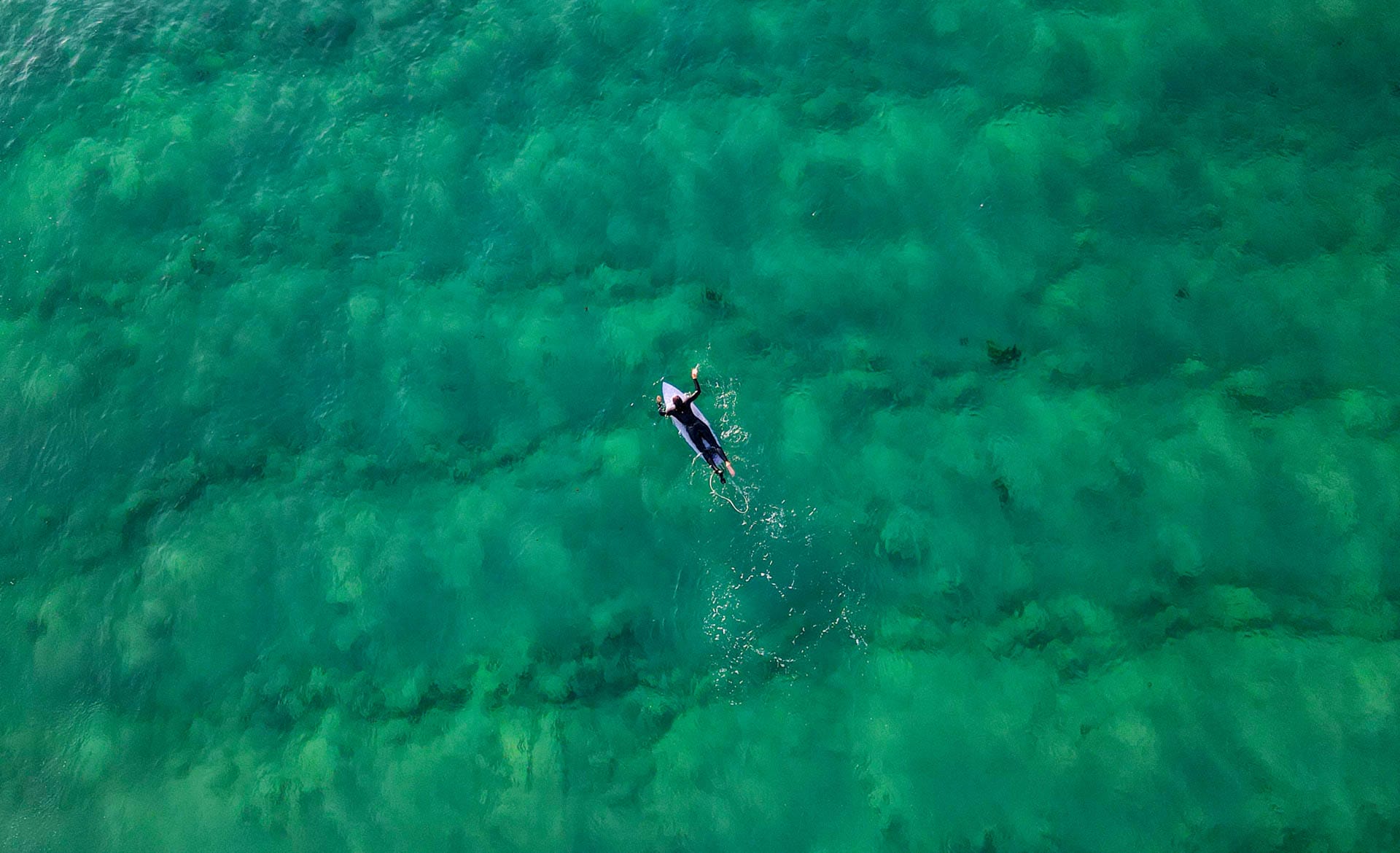 Wollongong Weekend Getaway Guide, Sharmali K, drone shot of person paddling out on surfboard in ocean