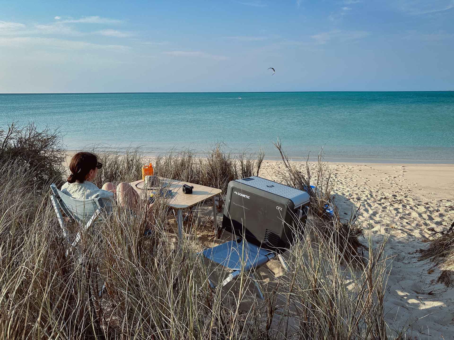 How a Dometic Fridge/Freezer Will Take Your Camping Set Up to the Next Level, gear, dometic, sponsored, beach picnic, lady having a picnic on the beach with a dometic freezer fridge