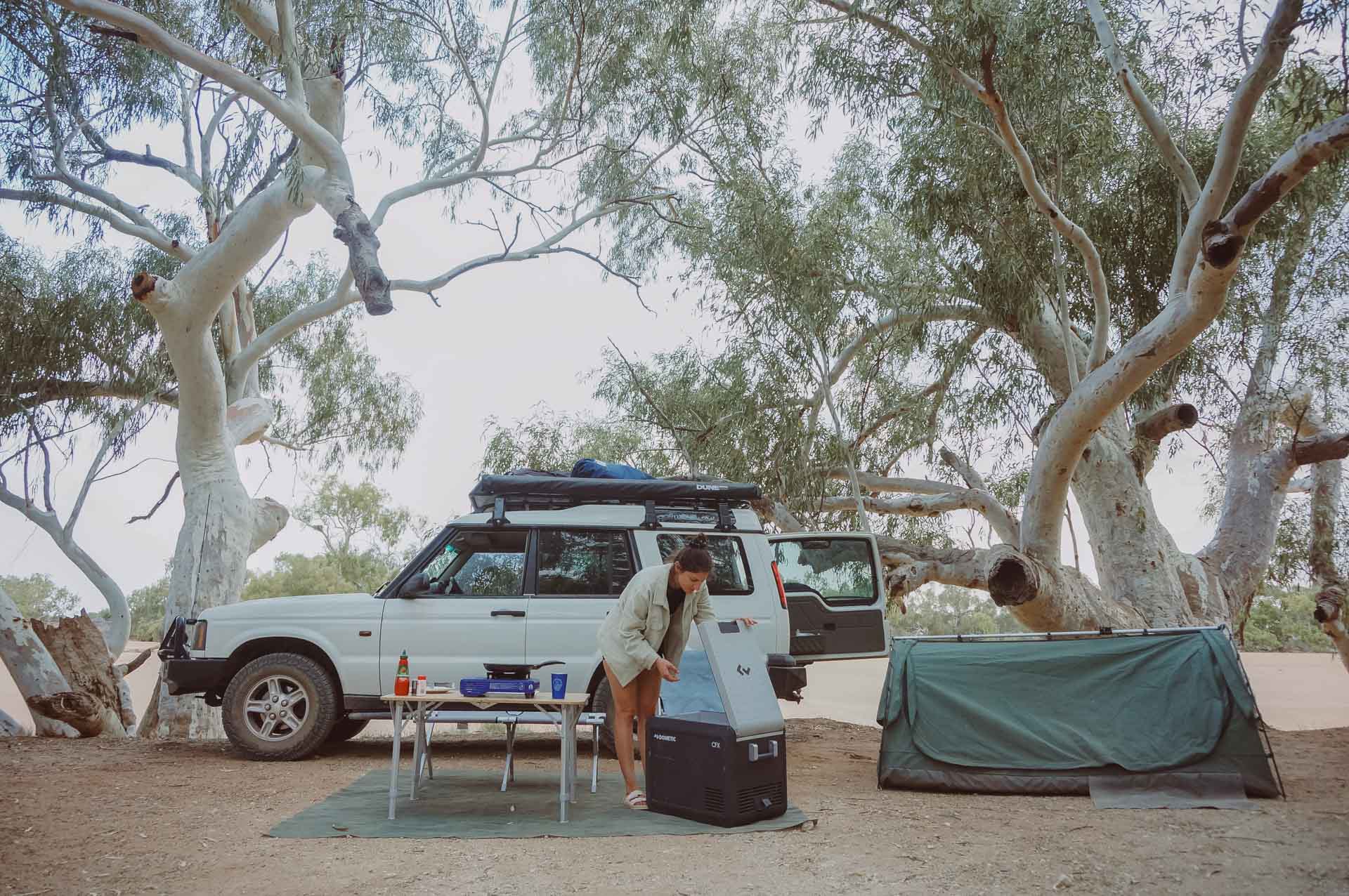 How a Dometic Fridge/Freezer Will Take Your Camping Set Up to the Next Level, gear, dometic, camping, camp cooking, lady going through dometic fridge while camping with a swag and 4WD