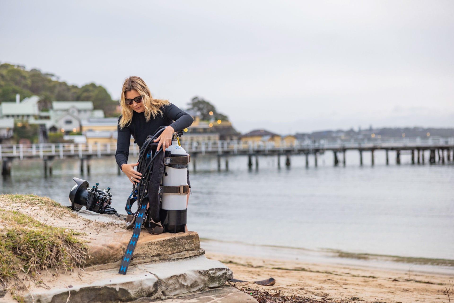 Meet Grumpy Turtle Films – The Company Telling Underwater Stories in The Name Of Conservation, conservation, photography, underwater photography, nature photography, marine life, lady preparing scuba gear in the shore of a beach with jetty in the background, sponsored, costa del mar