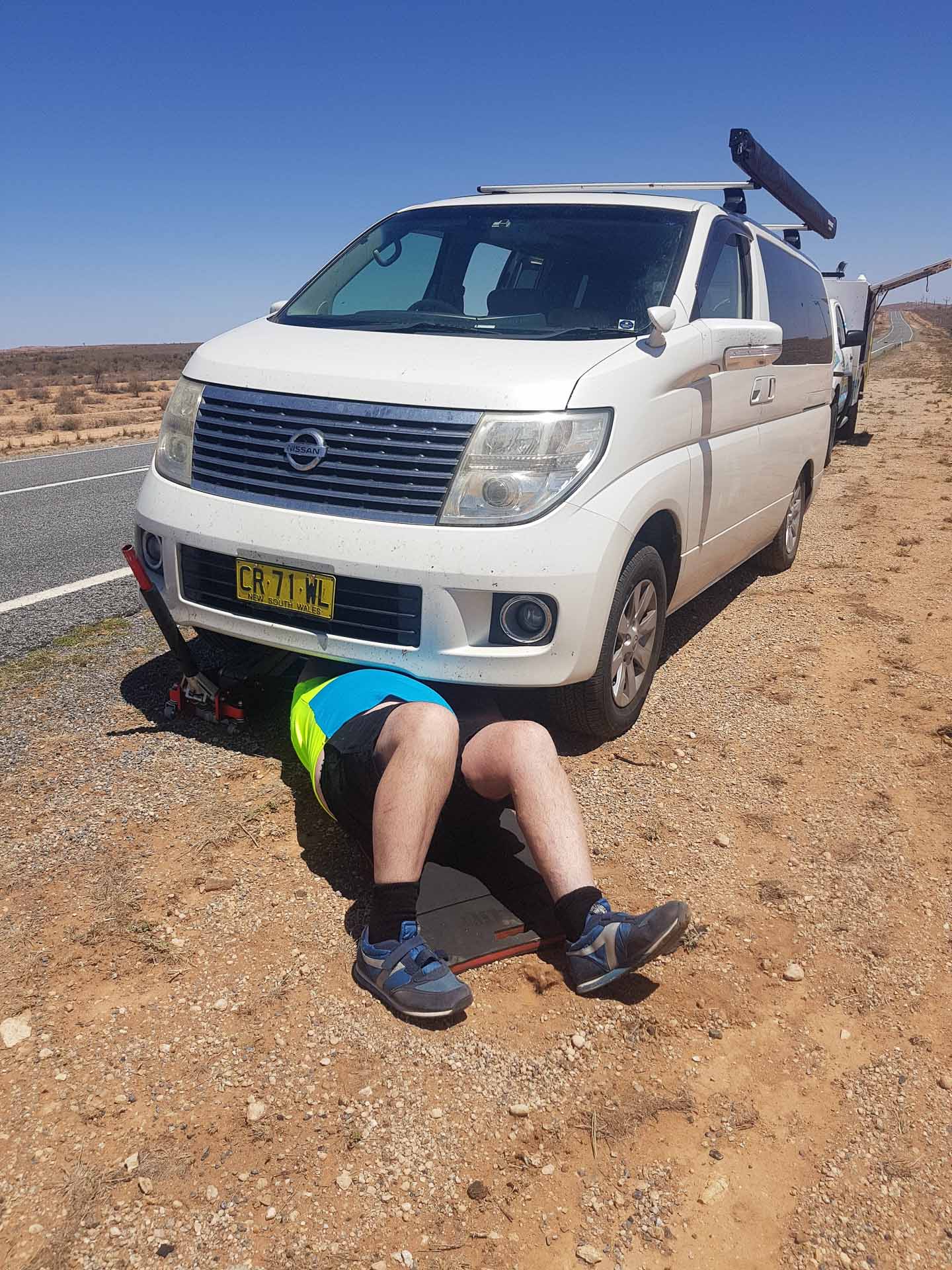 We Road Tripped From Sydney to Perth With a Three-Month-Old, roadtrip, van life, person checking underneath van in the desert