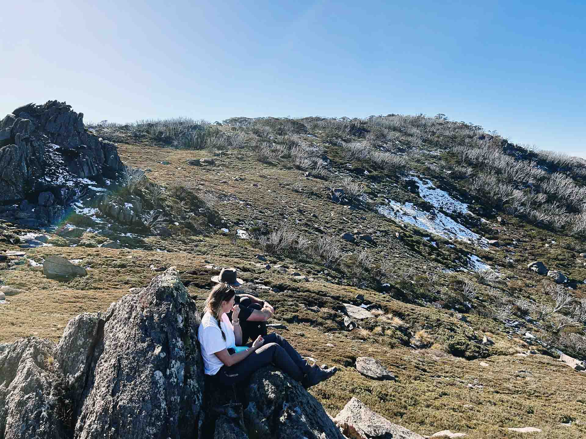 Charlotte Pass to Perisher Walk – Hiking the Newest Stage of the Snowies Alpine Walk in Kosciuszko National Park, nsw hikes, Photo by Kate Donald, alpine, back country, day hike, hikers sitting on rock with at kosciuszko