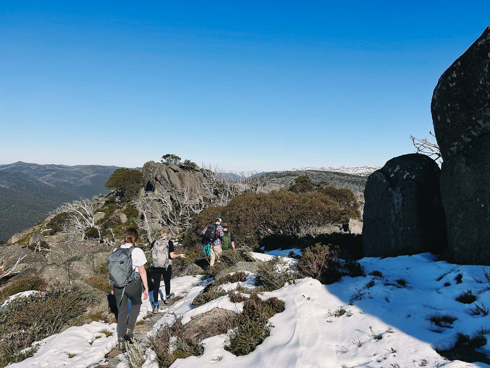 Charlotte Pass to Perisher Walk – Hiking the Newest Stage of the Snowies Alpine Walk in Kosciuszko National Park, nsw hikes, Photo by Kate Donald, alpine, back country, day hike, hikers on rocky and snowy trail at kosciuszko