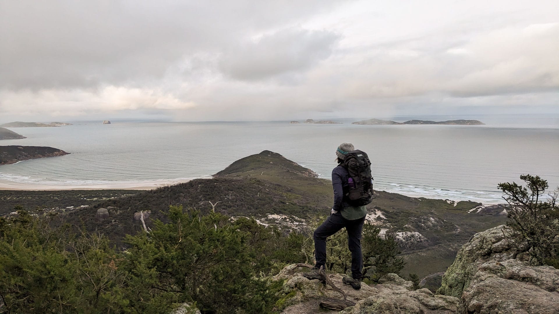 10 Best Day Hikes in Victoria, Photo by Jess Nehme, Mt Bishop summit, Wilsons Prom, lookout, beach, cloudy sky, hiker, backpack