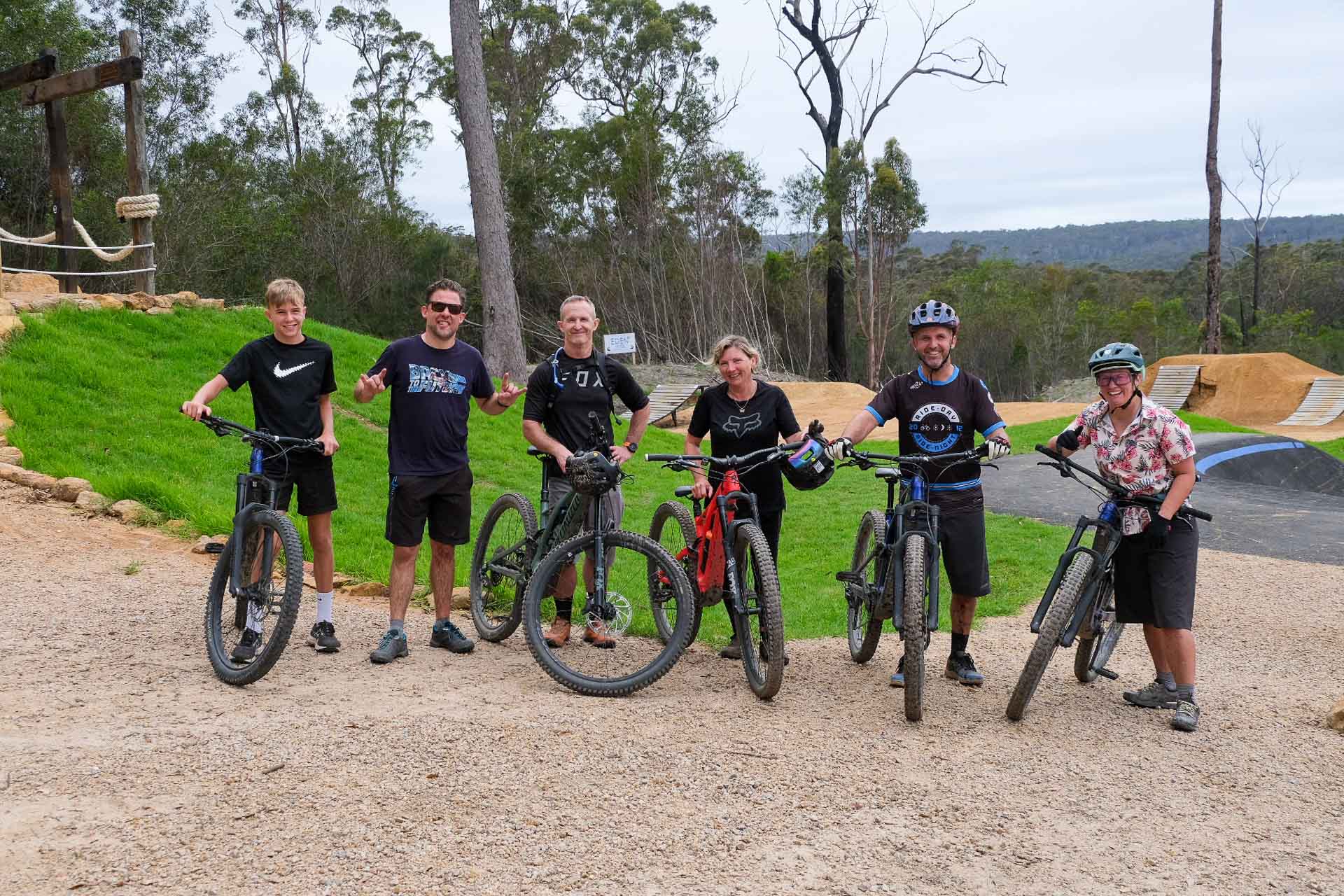 Gravity Eden – Dirt Surfing at NSW South Coast’s Newest Mountain Bike Park, Photo by Sarah Pendergrass, cycling, mountain biking, gravel biking, group photo of cyclists at gravity eden with dirt jumps in the background