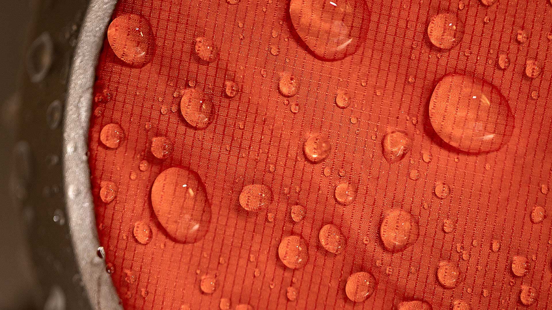 Your Rain Jacket Is Probably Harming The Planet – Here’s How That’s Changing, Photo by Tim Davis, water droplets on red fabric