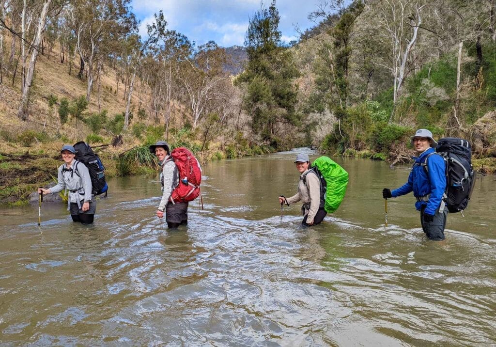 The Green Gully Track is NSW's Only Official Hut-to-Hut Multi-Day Hike, Emma Griffiths, friends, creek crossing, river, packs, hiking poles