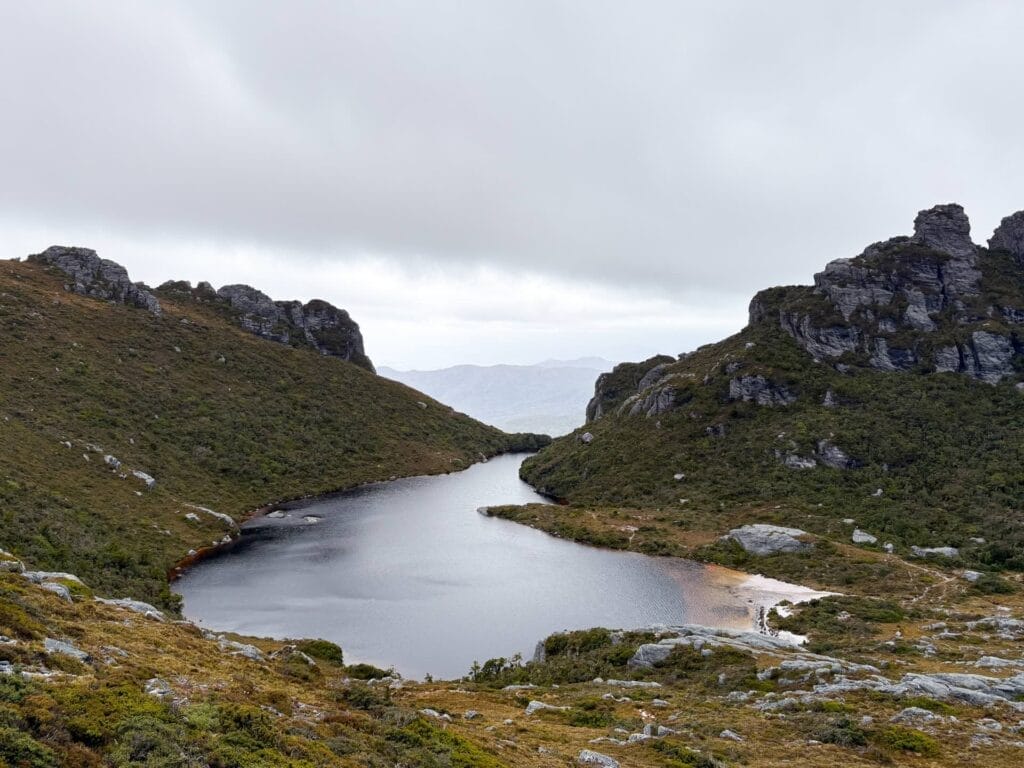Lake Cygnus, Western Arthurs Traverse, Tasmania, remote glacial lake, rugged mountains, cloudy sky, pristine wilderness, hiking destination