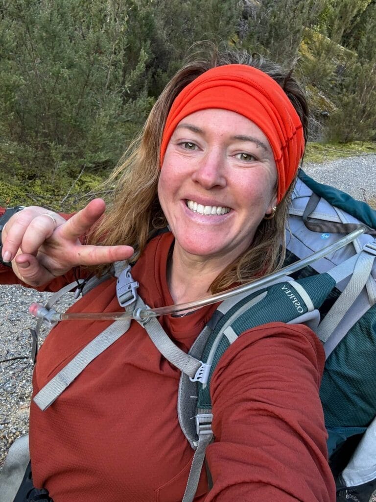Western Arthurs Traverse, Tasmania, by Lisa, smiling hiker, peace sign, hiking backpack, Alpha Moraine descent, multi-day hike, outdoor adventure