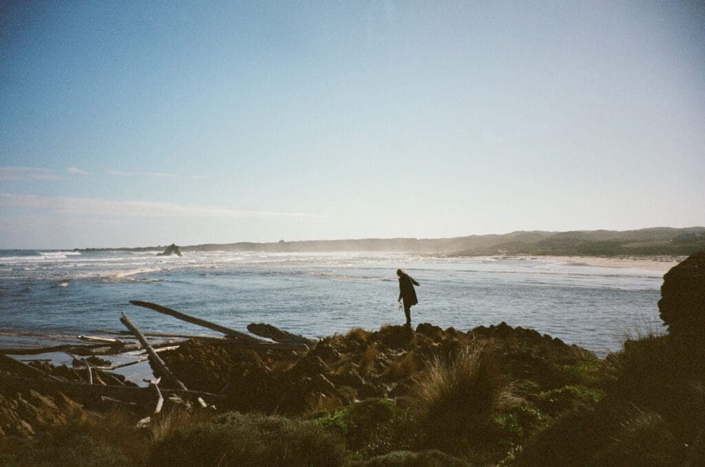 Rocky coastline, ocean view, waves, lone person, solitude, adventure, reflection, blue sky