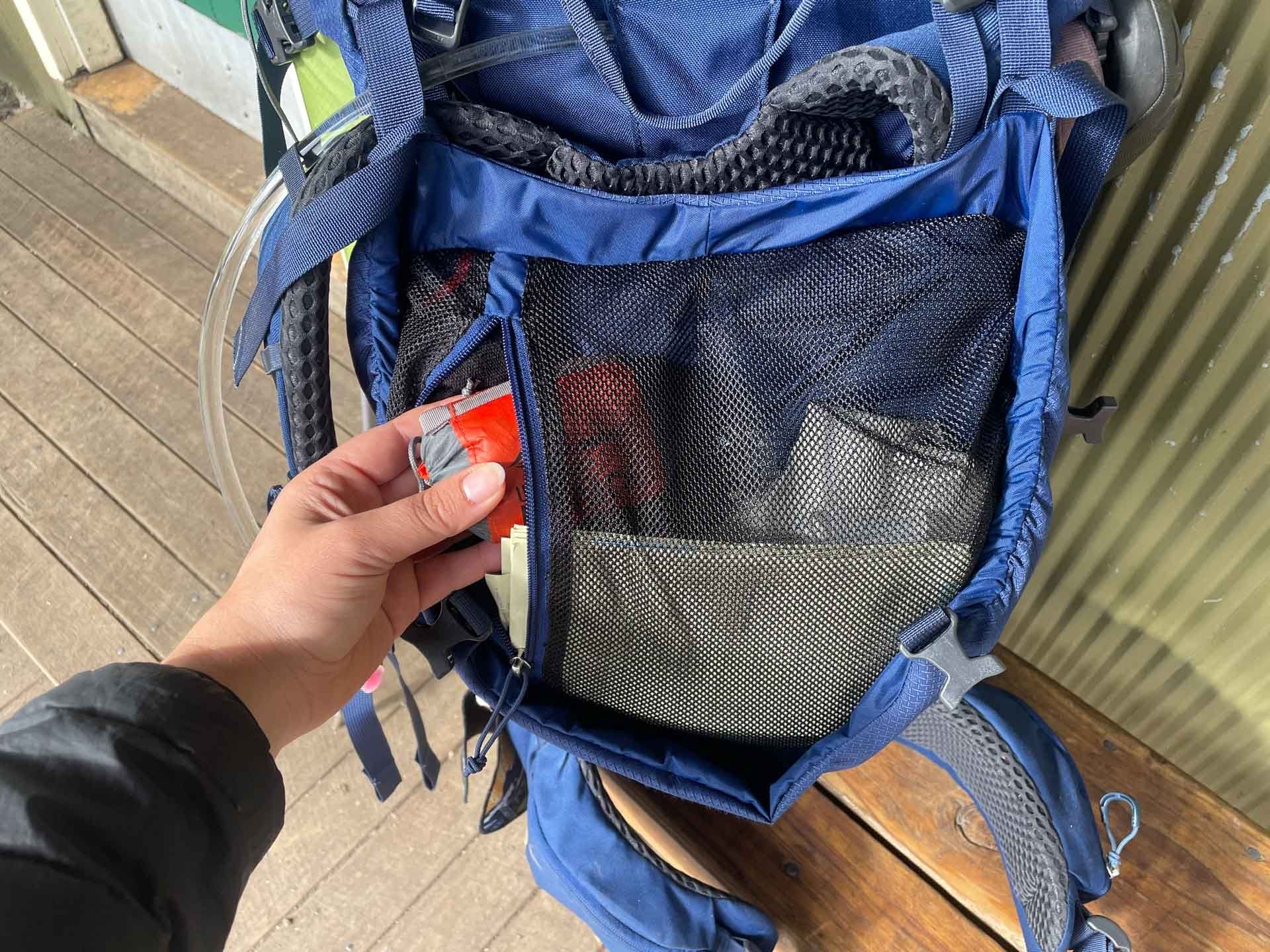 Osprey Kyte 65 Hiking Pack, internal mesh pocket, zippered pocket, hand accessing backpack, hiking gear, storage, multi-day adventures, hydration compatible, review