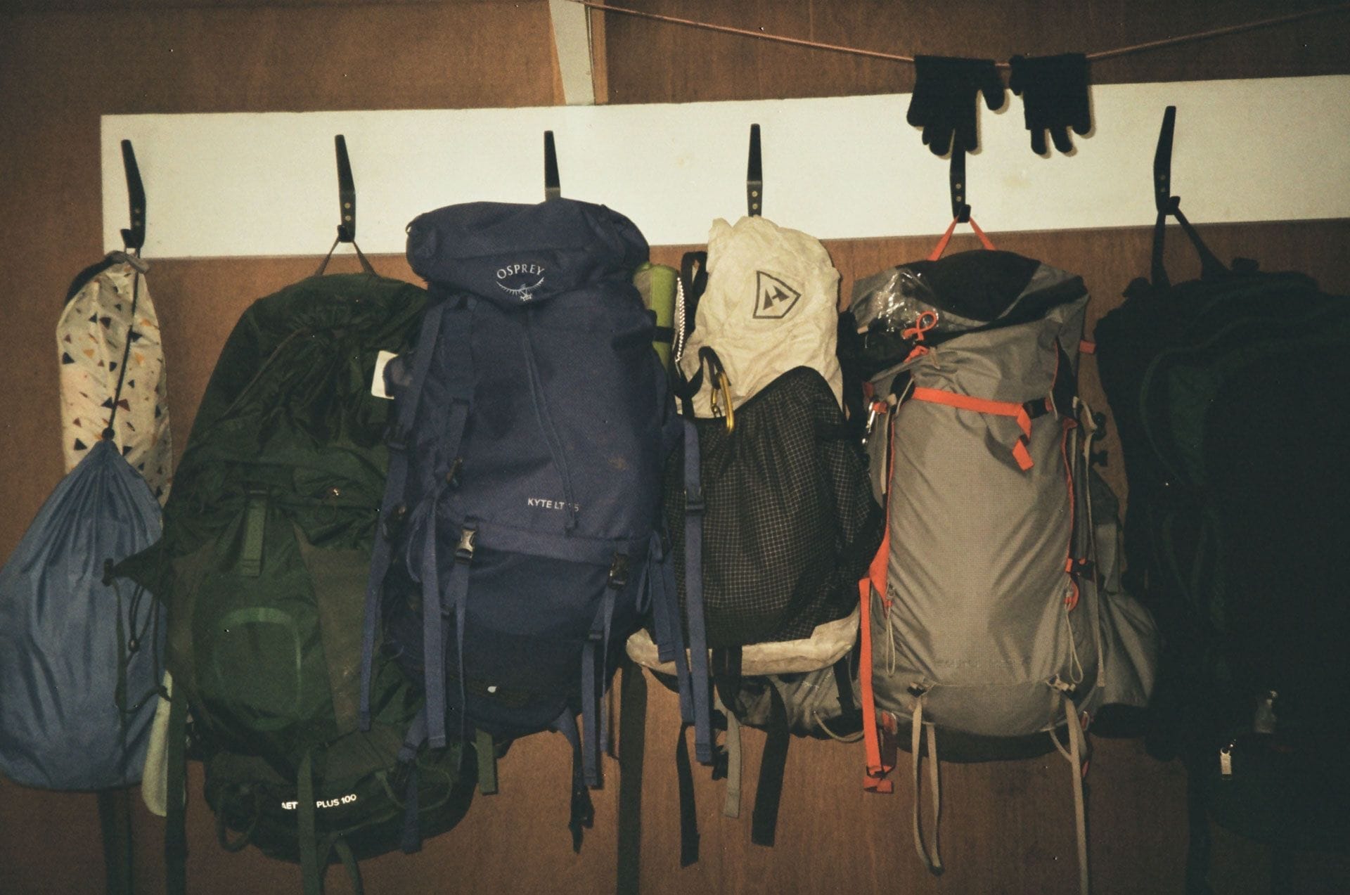 Hiking packs, Osprey Kyte LT 5, backpacking gear, multi-day adventure, outdoor equipment, hanging on wall, wooden interior, gear storage, Overland Track preparation