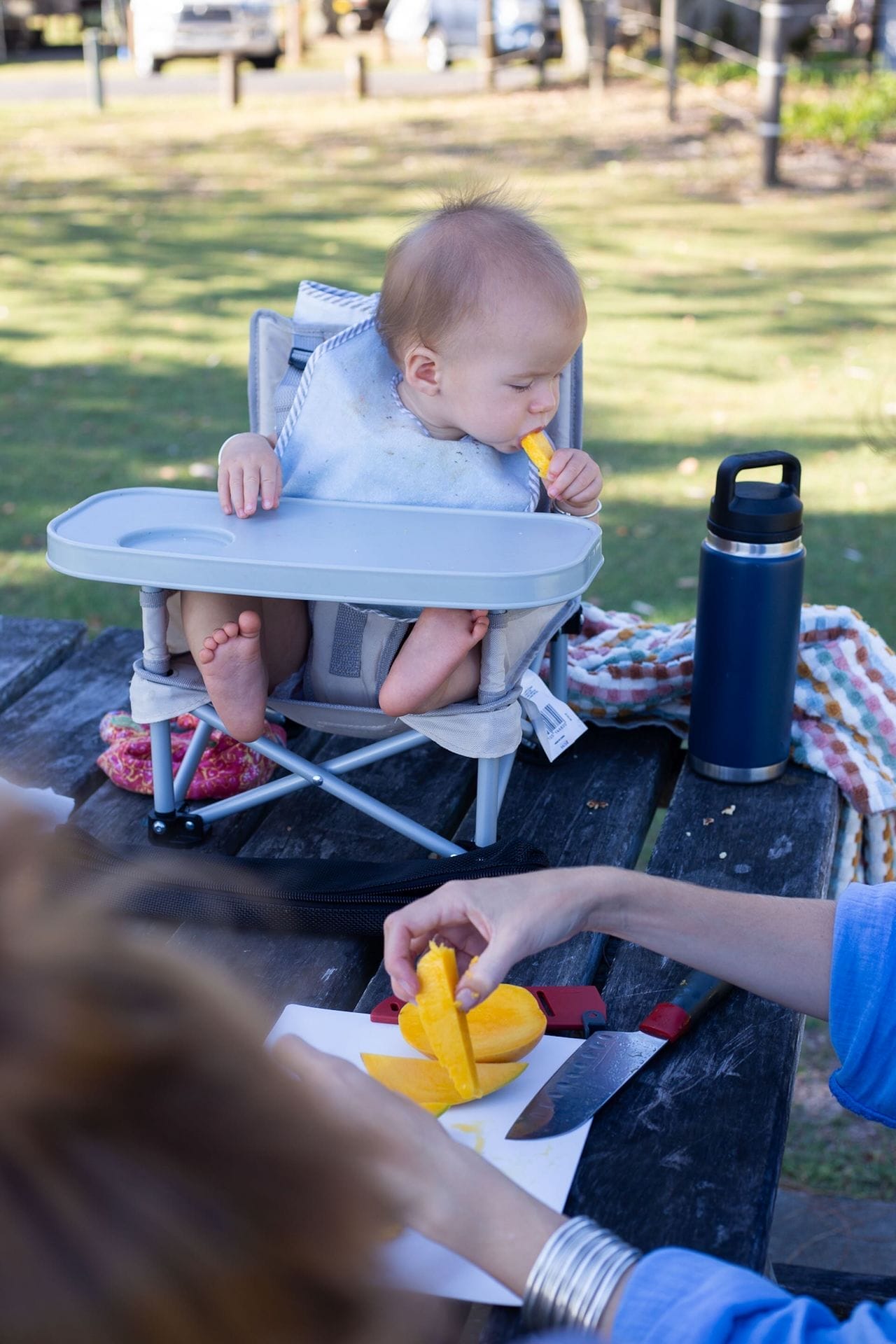 OXO camping gear, by Casey, baby eating mango, family camping, outdoor meal prep, portable high chair, picnic table, kids snacks