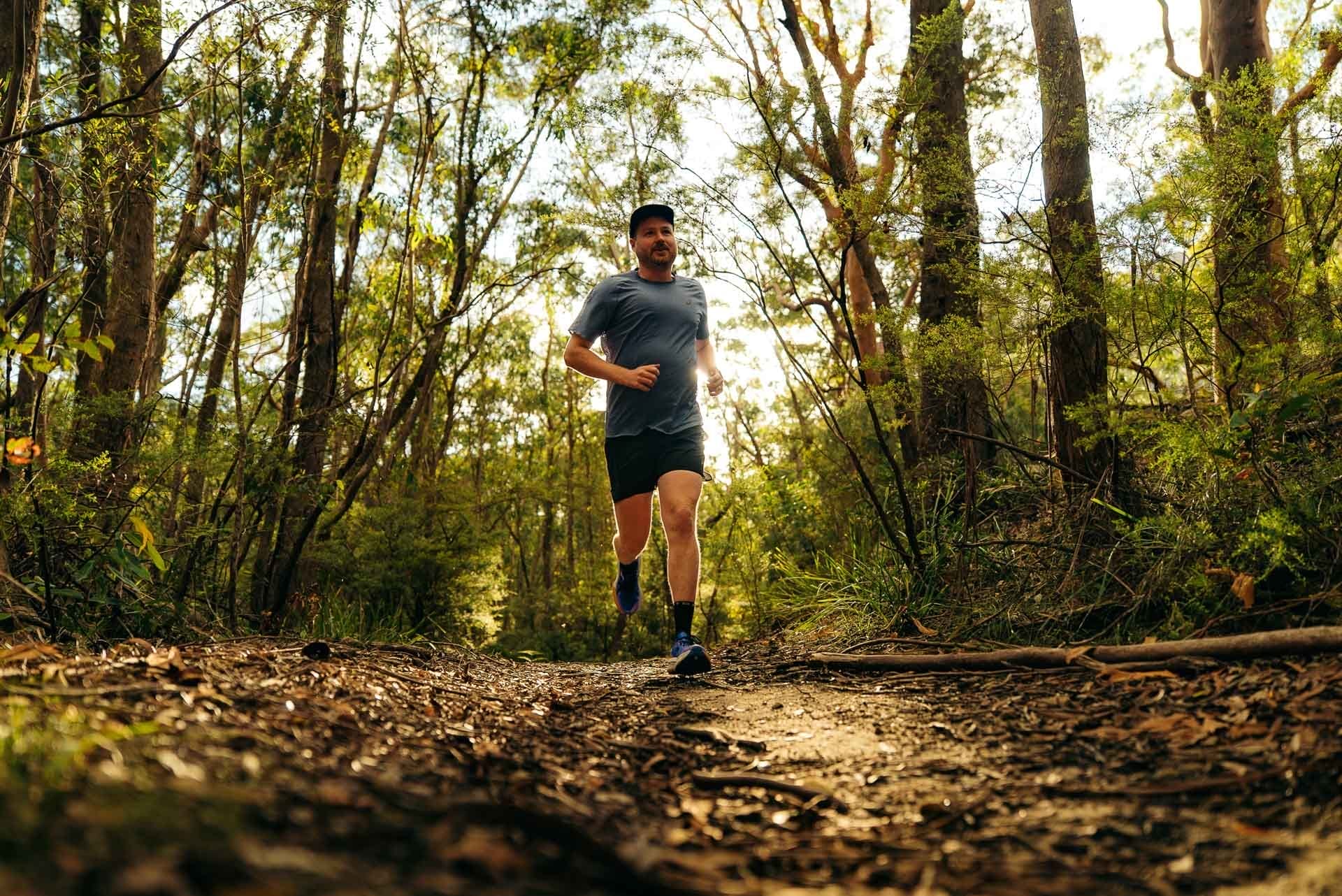 Tim trail running, Australian bush, by Paul, sunlight, forest, dirt path, outdoor adventure, We Are Explorers