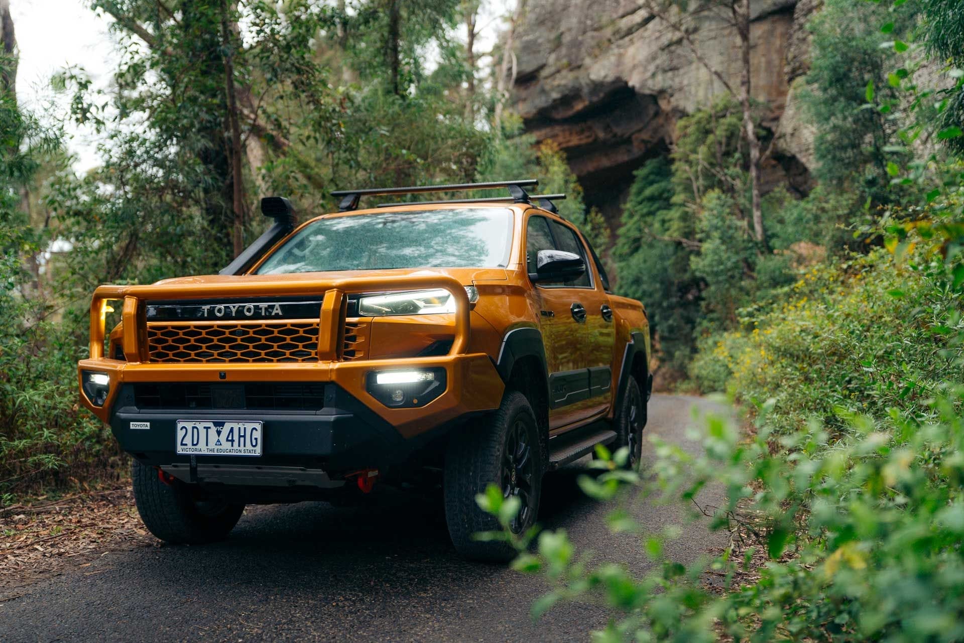 Toyota HiLux SR5, Victoria Australia, by Eva, orange pickup truck, bullbar, snorkel, roof racks, forest, rock formations, off-road, sunglow color, genuine accessories