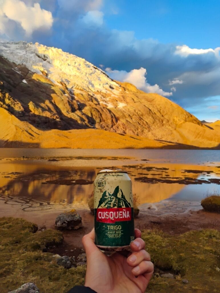 Ausangate, Peru, by Reece Johnston, Cusqueña Trigo beer, snow-capped mountains, lake reflection, golden hour, hiking comfort