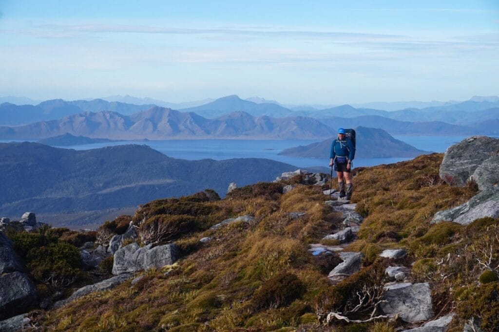 Tasmania Southwest wilderness, mountain landscape, distant lake, rocky trail, backpacker, multi-day hike, remote adventure