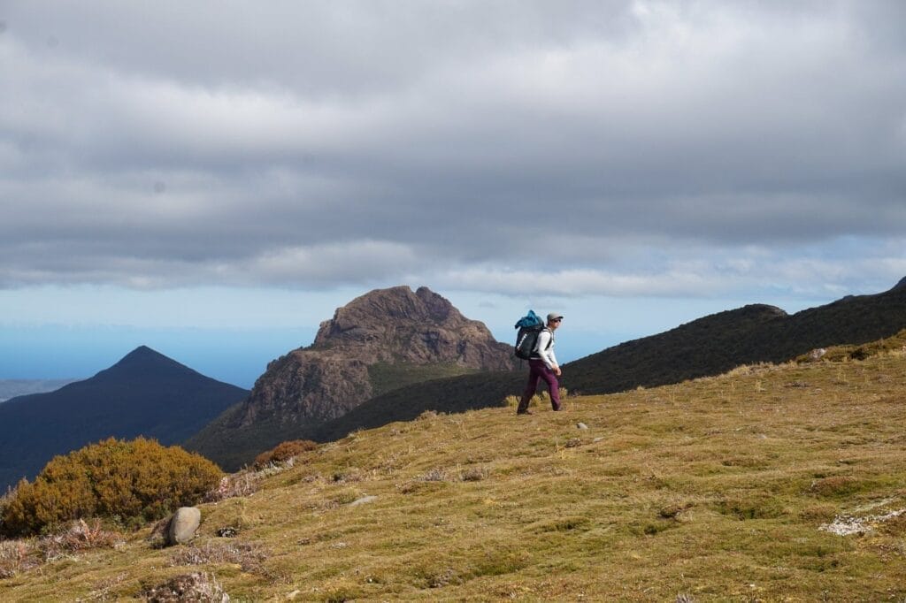 Tasmania, hiker, backpacker, mountain landscape, alpine meadows, rugged terrain, wilderness trails, cloudy sky