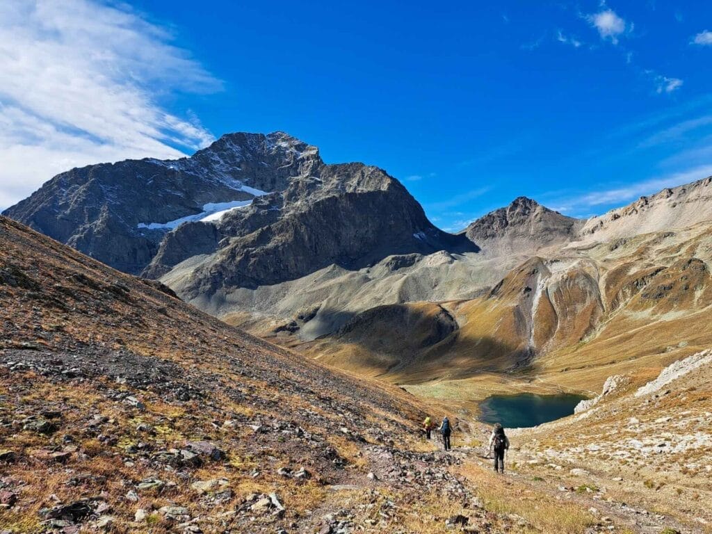 Lej da Suvretta, St Moritz Region, by Beckerhoff, mountain lake, hiking trail, alpine landscape, hikers, snowy peaks, rocky path, blue sky, Switzerland, backpacking, long-distance trail